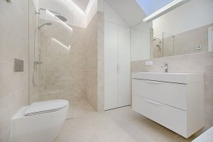 cream bathroom with white toilet, sink and cabinet, chrome shower