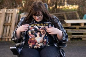Woman sat in wheelchair looking down at Labyrinth tshirt